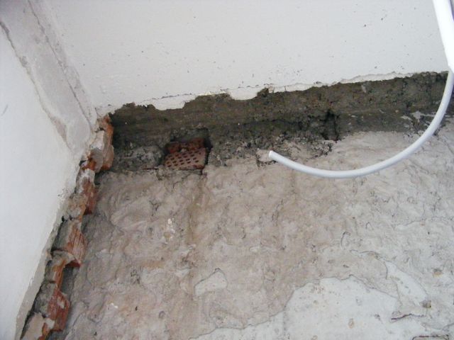 Colț de încăpere cu cărămizi dislocate și mortar de reparație sub o grindă